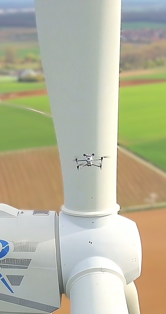 Eine Drohne der DrohnenVisite inspiziert den Rotor einer Windenergieanlage (WEA). Die gesamte Fläche wird durch eine KI-Steuerung fotografisch hochauflösend erfasst und an eine KI Software zur Oberflächen-Analyse übermittelt. Der Einsatz von Drohnen ist dabei viel schneller und kostengünstiger als der Einsatz von Industriekletterern.